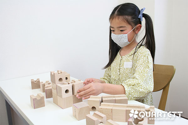 小学生の女の子がキュボロで道を作っています