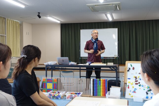 保育環境改善プログラム 園内研修 構成遊び ビーズボードを前に説明する藤田代表理事