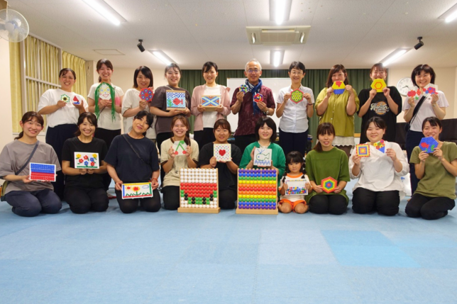 保育環境改善プログラム 構成遊び研修 完成した作品を手に笑顔の先生方と藤田代表理事