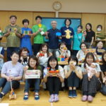 研修参加者がおのおのに玩具を手に持ち、講師を囲んで撮影した集合写真