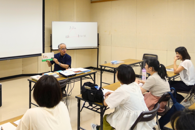 1冊の絵本を通して物語の世界を分かち合う講師と、それに耳を傾ける参加者たち