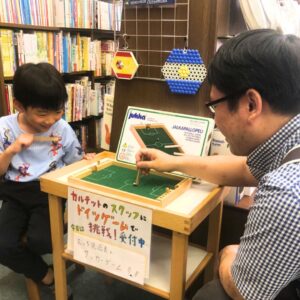 むっち兄店長とユシラ社のサッカーゲームで対戦する子ども