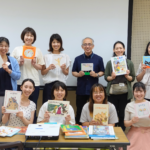 講師を囲み、それぞれお気に入りの絵本を手に持って並ぶ研修参加者の集合写真
