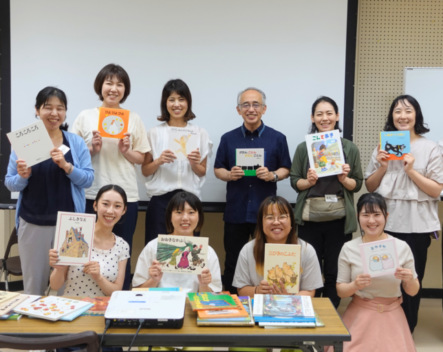 講師を囲み、それぞれお気に入りの絵本を手に持って並ぶ研修参加者の集合写真
