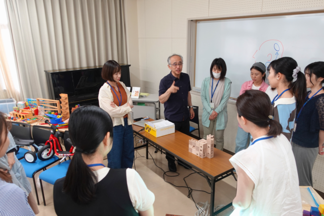 積木で組んだ作品を囲み、講師の説明に耳を傾ける参加者たち